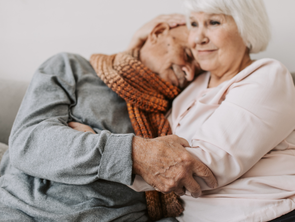 An elderly couple hugs each other